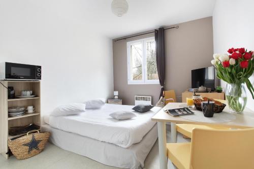 ein Schlafzimmer mit einem Bett und einem Tisch mit einer Blumenvase in der Unterkunft Neoresid - Résidence Saint Germain in Amiens