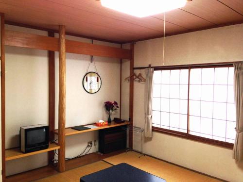 a living room with a tv and a window at Naeba Lodge Oka in Yuzawa