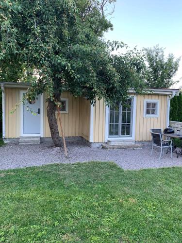 a house with a table and a chair and a tree at Mysigt gårdshus på vackra Stensö in Kalmar