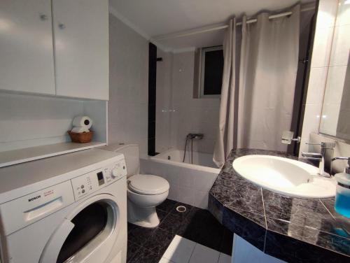 a bathroom with a washing machine and a sink at Euphoria Apartment in Nafplio
