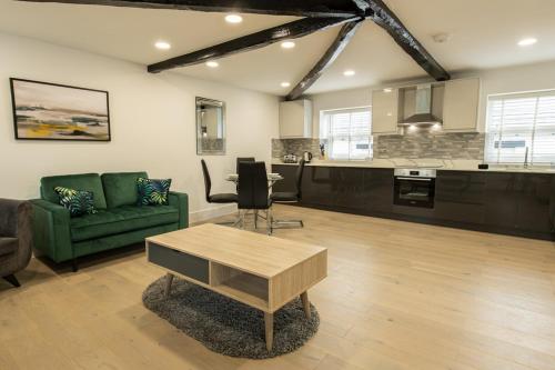 Una sala de estar con un sofá verde y una cocina. en Coniston House near Bolton, Appleby-in-Westmorland by Guestz, en Kirkby Thore