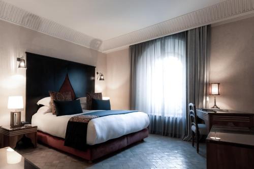 a hotel room with a large bed and a desk at Riad Fes - Relais & Châteaux in Fès