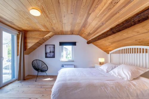デュルビュイにあるMaison Loïcの白いベッドと木製の天井が備わるベッドルーム1室が備わります。