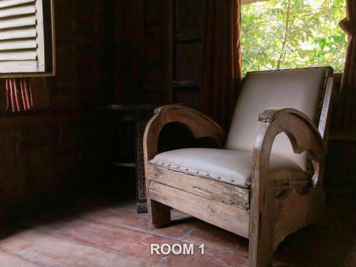 an old chair sitting in a room with a window at Sweet Orange Pondok in Ubud