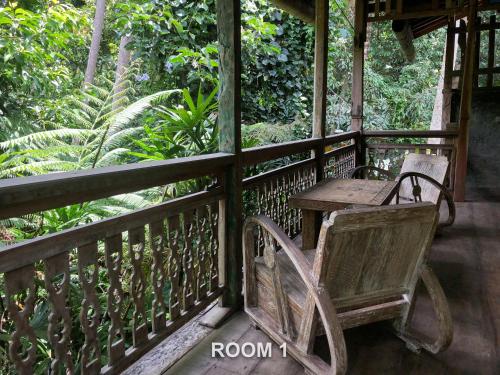 a wooden porch with a table and a chair on it at Sweet Orange Pondok in Ubud