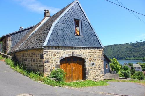 ein altes Steingebäude mit einer großen Tür und einem Fenster in der Unterkunft Maison de Varennes in Chambon-sur-Lac