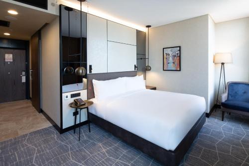 a bedroom with a large white bed and a blue chair at Dedeman Kartepe Kocaeli in Kocaeli