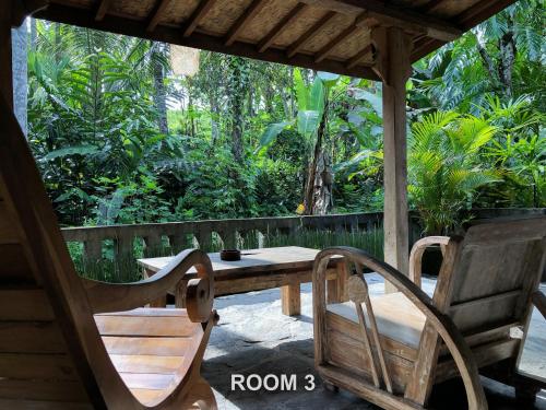 a wooden porch with a wooden table and chairs at Sweet Orange Pondok in Ubud