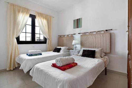 two beds in a room with white walls and windows at Villa Hibiscus in Playa Blanca