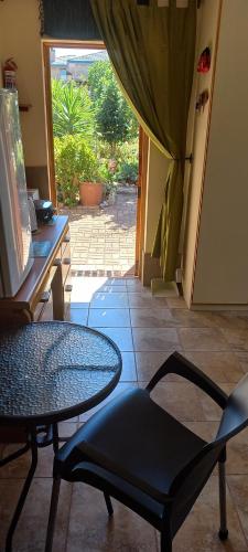 a room with a table and a chair and a glass table at Whispering Gardens in Stilbaai