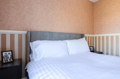 a bedroom with a bed with white pillows at George Harrison's Former 3Bed Home in Liverpool in Speke