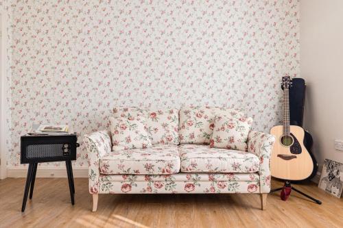 a living room with a couch and a guitar at George Harrison's Former 3Bed Home in Liverpool in Speke