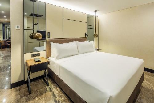 a bedroom with a large white bed and a table at Dedeman Kartepe Kocaeli in Kocaeli