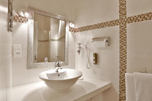 a white bathroom with a sink and a mirror at Hotel Restaurant Charbonnel in Brantôme