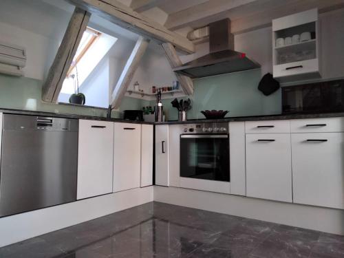 uma cozinha com armários brancos e um fogão em Dachgeschosswohnung-15min vom Europa Park entfernt em Kenzingen