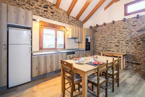 cocina con mesa de madera y nevera blanca en O Trancallo, en Viana do Bolo