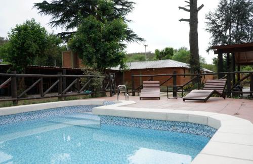 uma piscina com duas cadeiras e uma mesa em Cabañas Buen Dia em Villa Serranita