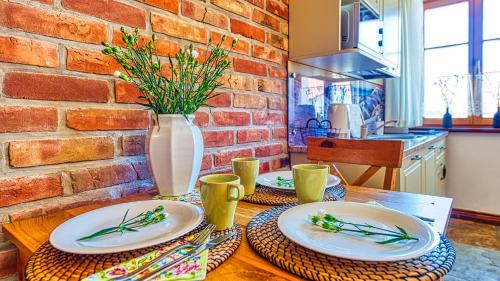 una mesa con dos platos y un jarrón con flores en Aparthotel STARA PIEKARNIA by ROYAL APARTS, en Szklarska Poręba