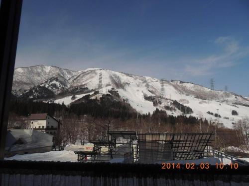a snow covered mountain in front of a ski slope at Naeba Lodge Oka in Yuzawa