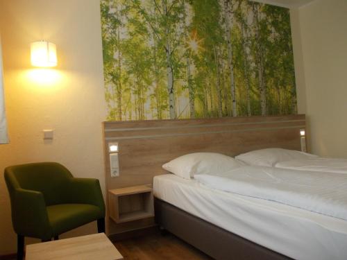 a bedroom with a bed and a green chair at Berghotel Glockenberg in Sankt Andreasberg