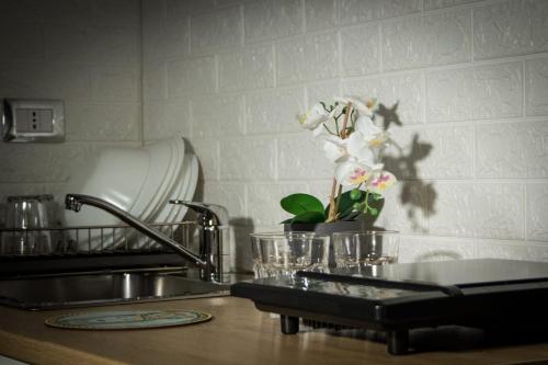 a kitchen counter with a sink and a vase of flowers at J&S Sicily Apartments in Catania