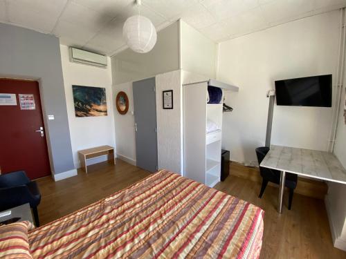 a bedroom with a bed and a desk and a tv at Hôtel Belle Vue d'Angleterre in Le Grau-du-Roi