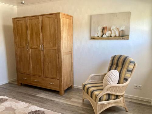 a living room with a chair and a cabinet at Kalverkamp Ferienwohnung in Lieser
