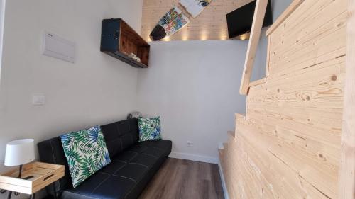 a living room with a black couch and a wooden wall at Family Surf Home - Casa do Páteo 5 in Santo Isidoro