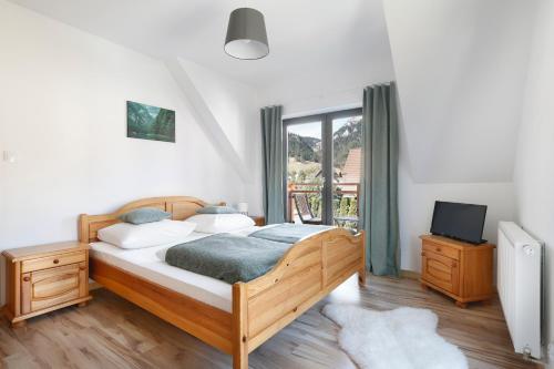 a bedroom with a bed and a tv and a window at Willa Widok in Sromowce Niżne