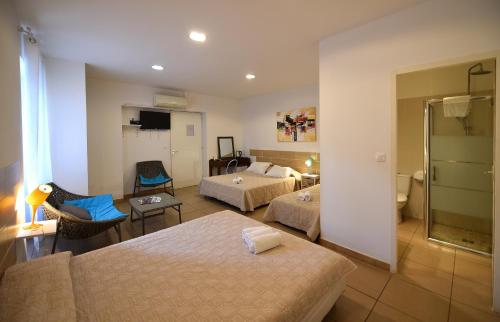 a hotel room with two beds and a bathroom at Hôtel A casa di Maria Cicilia in Ghisonaccia