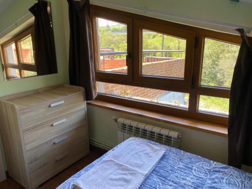 a bedroom with two windows and a bed and a dresser at Apartamentos Turísticos Casa Nieves in La Franca