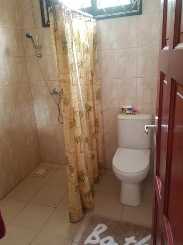 a bathroom with a toilet and a shower with a shower curtain at Arcton Apartment in Paramaribo