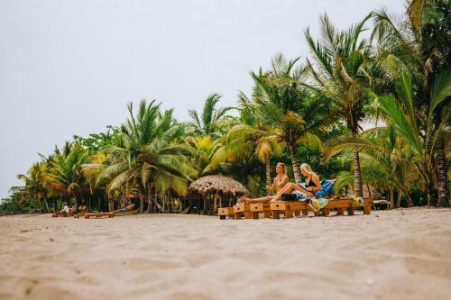 two people sitting in chairs on the beach at Viajero Tayrona Hostel & Ecohabs in Buritaca