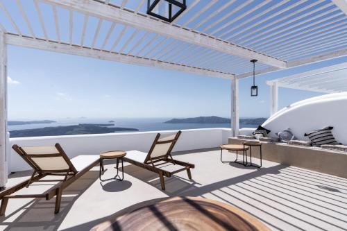 Un balcón con sillas y una mesa en un yate en Imera Vista Suites en Imerovigli