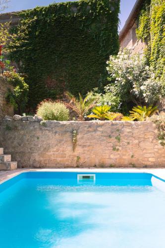 une grande piscine bleue à côté d'un mur en pierre dans l'établissement Le Chai de Marguerite, à Peyriac-Minervois