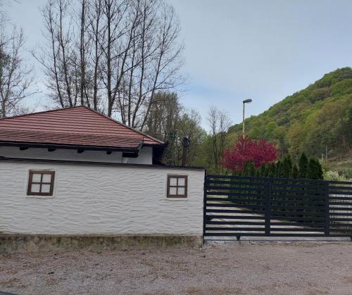 a white building with a red roof next to a fence at ATRIUM Holiday home in Bihać