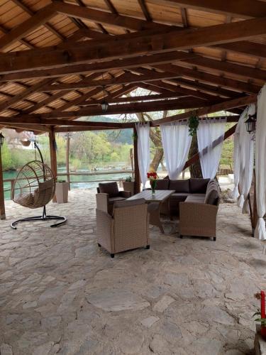 a patio with a couch and chairs under a wooden roof at ATRIUM Holiday home in Bihać