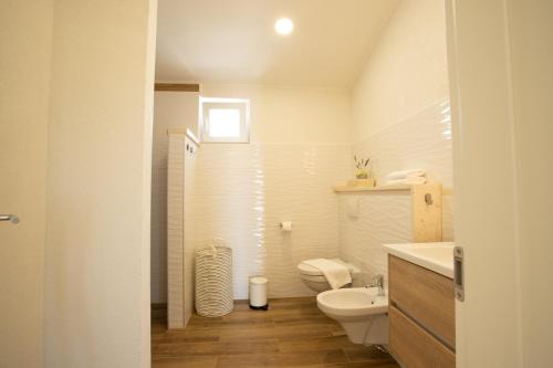 a white bathroom with a toilet and a sink at BUKY HOUSE in Sumartin
