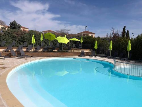 une grande piscine bleue avec des chaises et des parasols dans l'établissement Camping Forcalquier les Routes de Provence, à Forcalquier