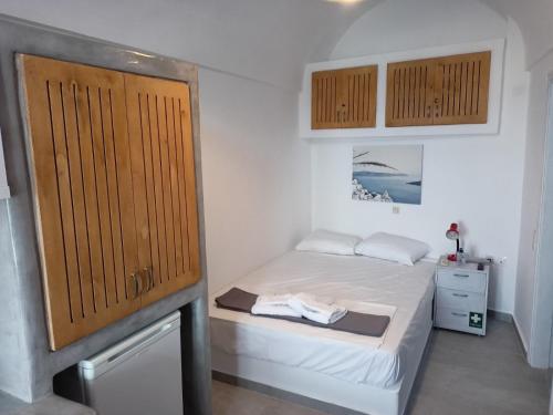 a small bedroom with a bed and a wooden door at VI STA FINIKIAS VILLA in Oia