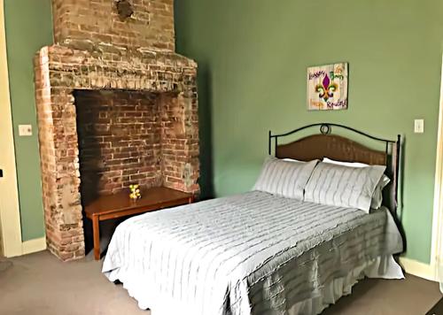 a bedroom with a bed and a brick fireplace at Historic Viavant Cottage - Jazz Fest/FairGrounds in New Orleans