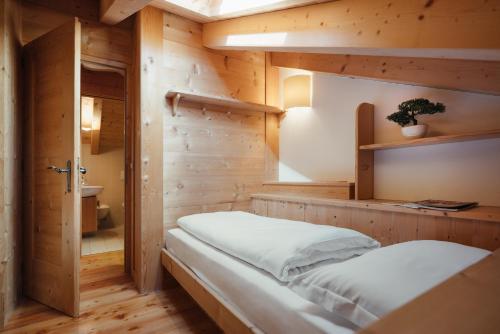una camera con un letto su una parete in legno di BelaVal Apartments a La Villa