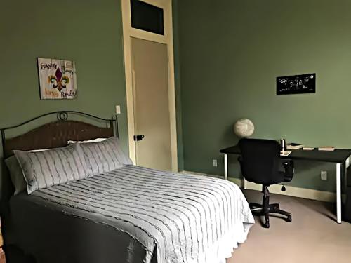 a bedroom with a bed and a desk and a computer at Historic Viavant Cottage - Jazz Fest/FairGrounds in New Orleans