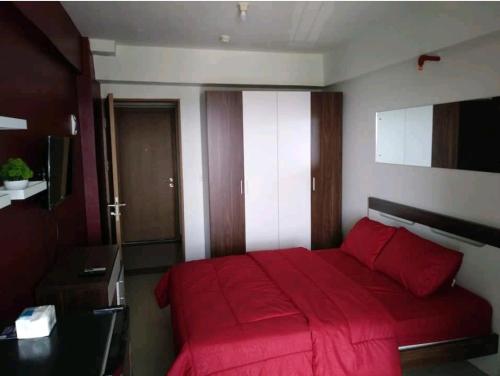 um quarto com uma cama vermelha e um cobertor vermelho em Bintaro Parkview A1228 em Jakarta