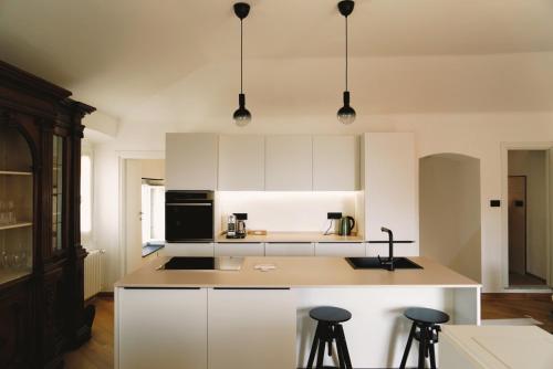 a kitchen with white cabinets and a island with bar stools at Appartamento Villa Cristina in Genoa