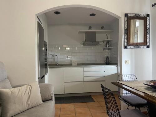 una cocina con armarios blancos y una mesa con sillas. en APARTAMENTO RURAL CASA MONTE, en Cazalla de la Sierra