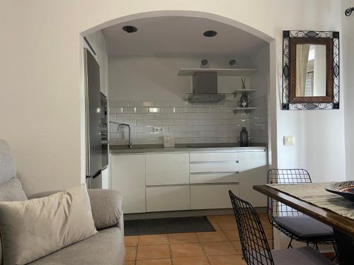 a kitchen with white cabinets and a table with chairs at APARTAMENTO RURAL CASA MONTE in Cazalla de la Sierra