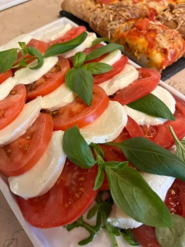 a plate of food with tomatoes and cheese and pizza at Hotel Porto Azzurro in Sirmione