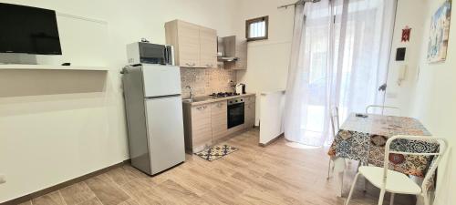 a kitchen with a refrigerator and a table with chairs at Kiberosa in Isola delle Femmine