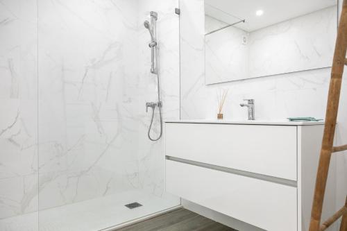 a white bathroom with a shower and a sink at Consolação Terrace in Consolacao